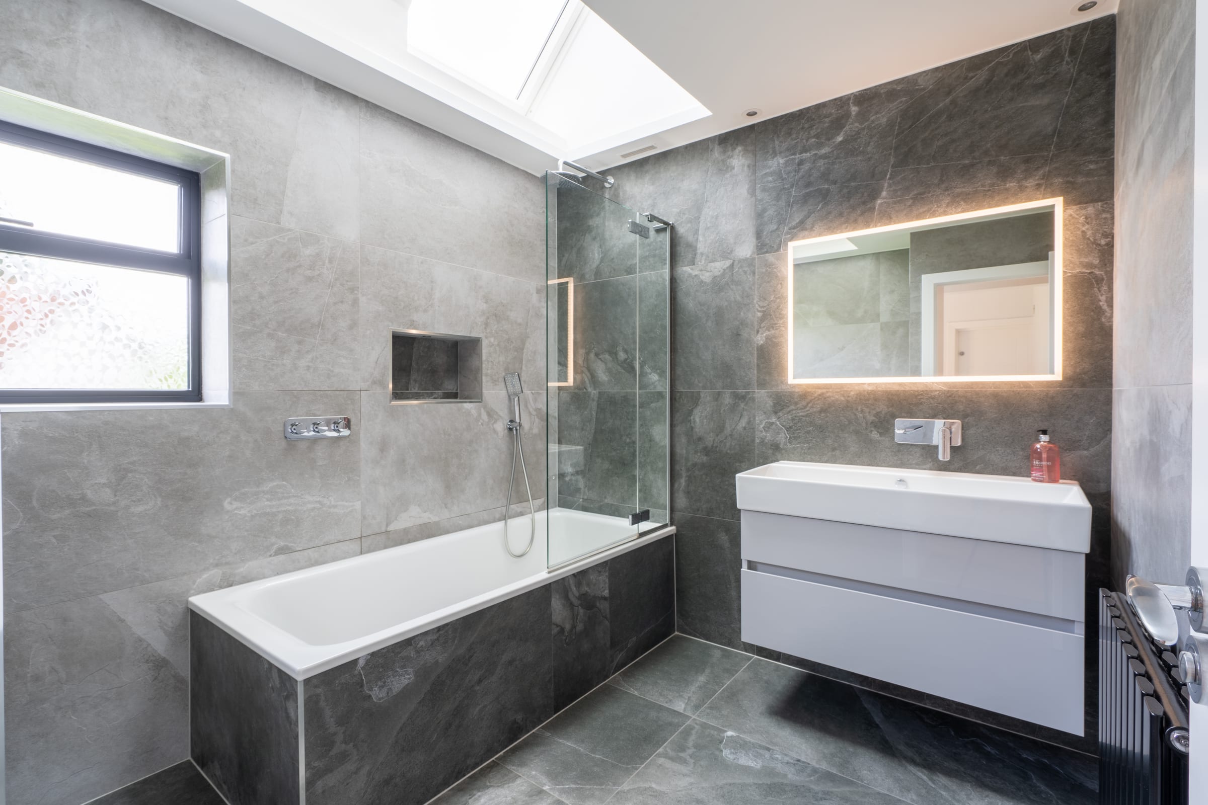 Principal bathroom with grey marble tiling and backlit mirror, Chorleywood.