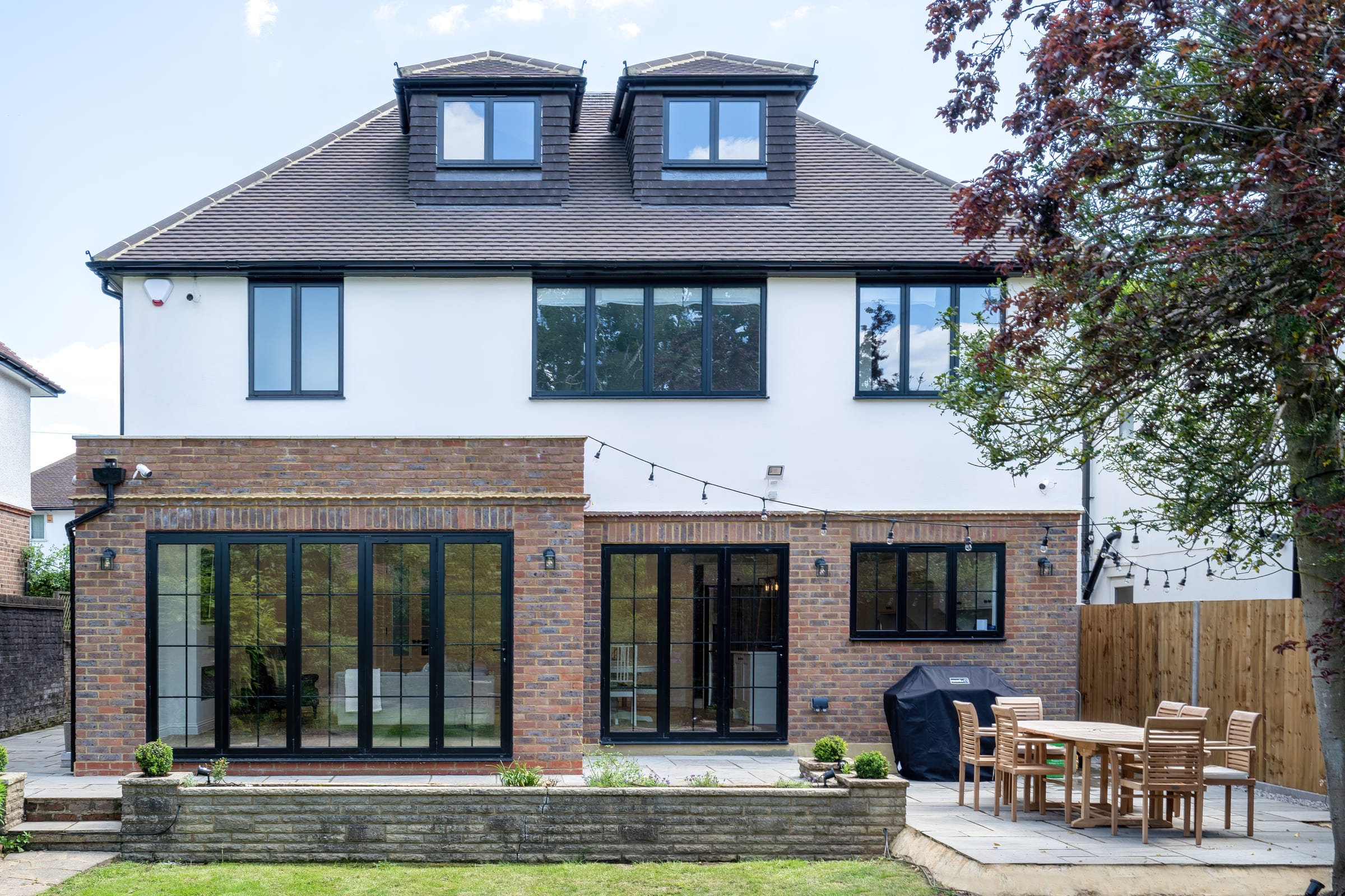 HXL rear elevation with white render, red brick and bifolds to garden, Chorleywood.
