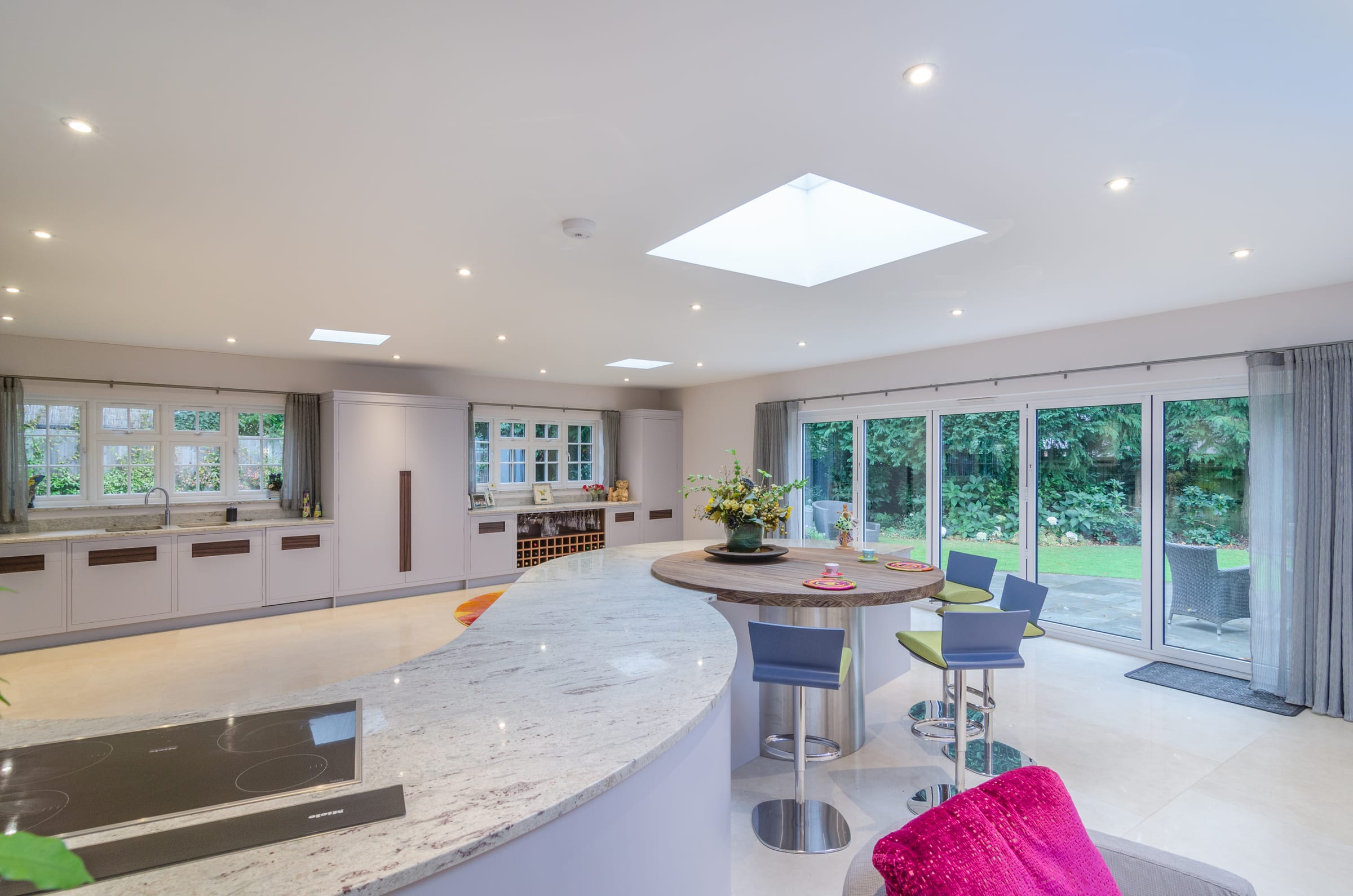 HXL interior fit-out. Curved island kitchen with bifolds to garden, Vicarage Way.