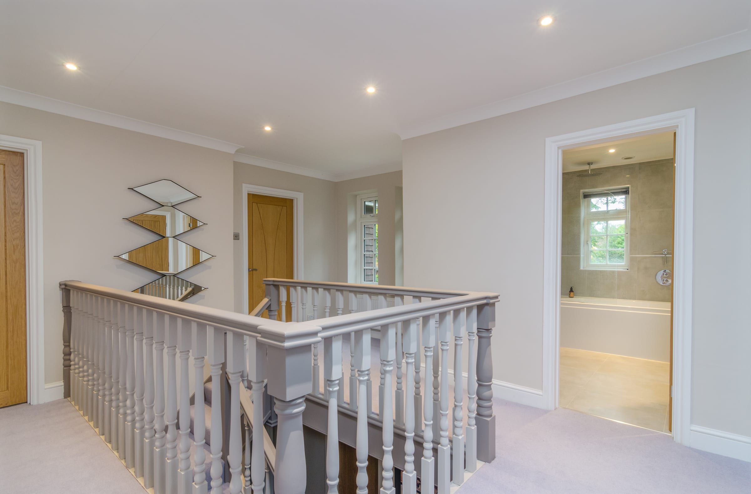 First-floor landing with painted spindle balustrade, oak doors and view through to bathroom, Vicarage Way.